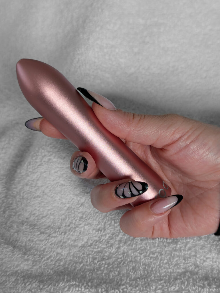 DOXY Bullet i metallisk roséguld hålls mellan fingrar